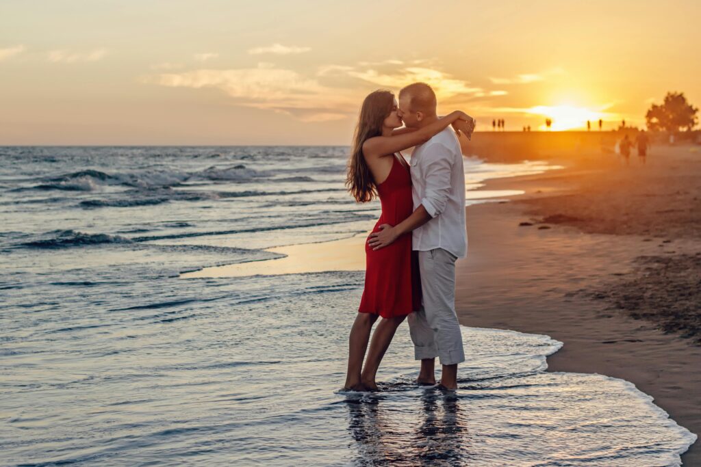 Couple kissing on beach during golden hour